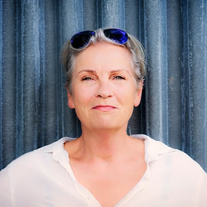 Portrait von fraujahnke mit Sonnenbrille in den Haaren vor samtig-blauem Vorhang.