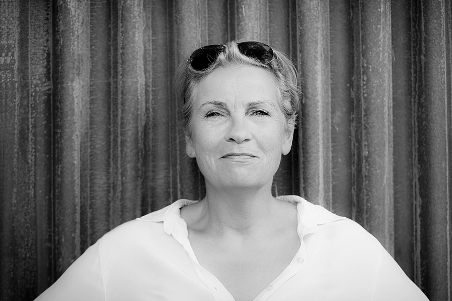 Portrait von fraujahnke in schwarz-weiß mit Sonnenbrille in den Haaren vor samtigem Vorhang.